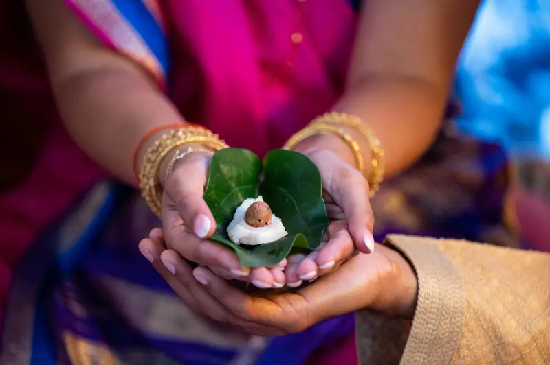 Hands holding betel leaves during a wedding ritual